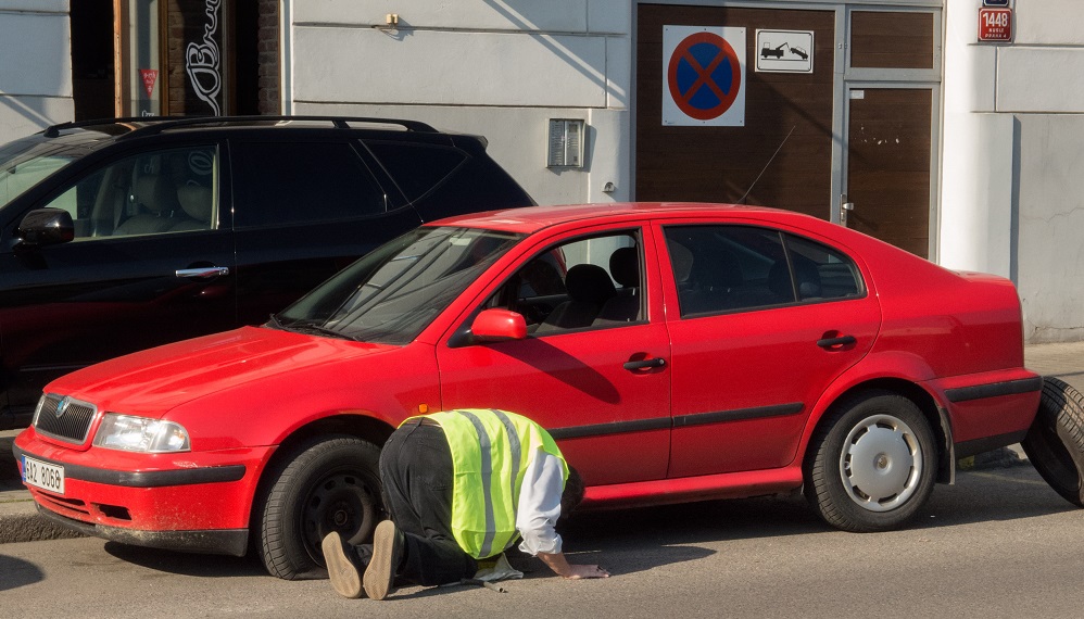 Man changing the punctured tyre on the red car